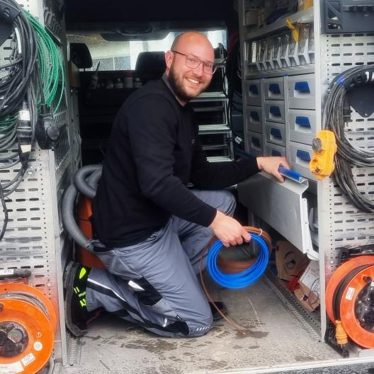 Ein Elektro Brockbals Mitarbeiter sortiert Kabel in einem Firmenwagen